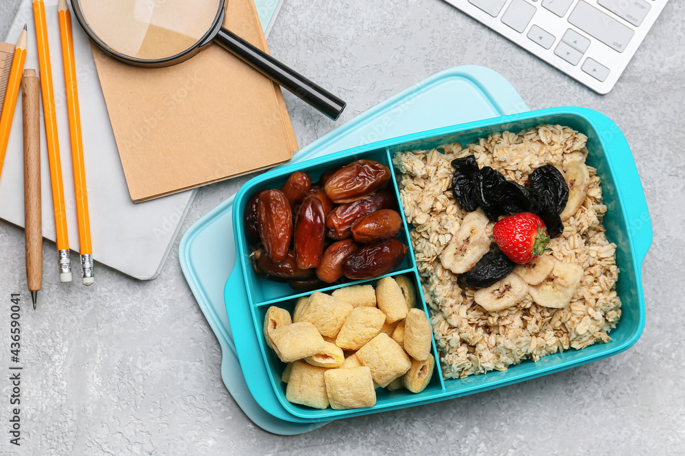 Lunchbox with tasty food and stationery on light background