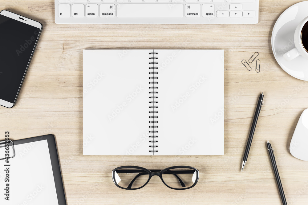 Stylish work table with blank notebook pages, keyboard, glasses, smartphone and coffee mug on wooden