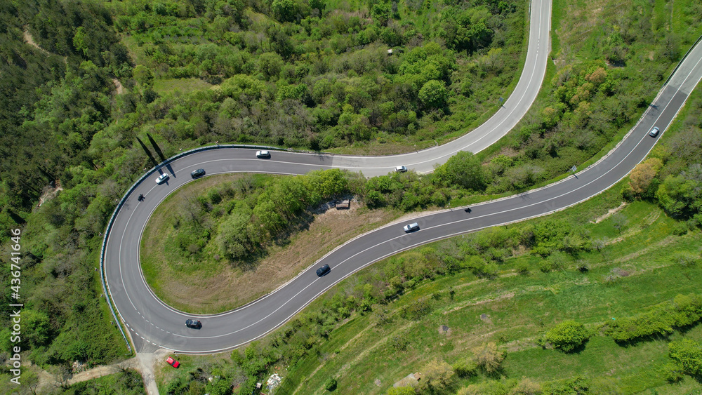 空中俯视图：公路旅行的游客正开车穿过一个急转弯。