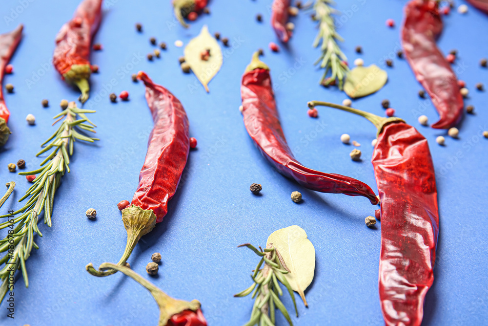 Hot chili peppers and spices on color background