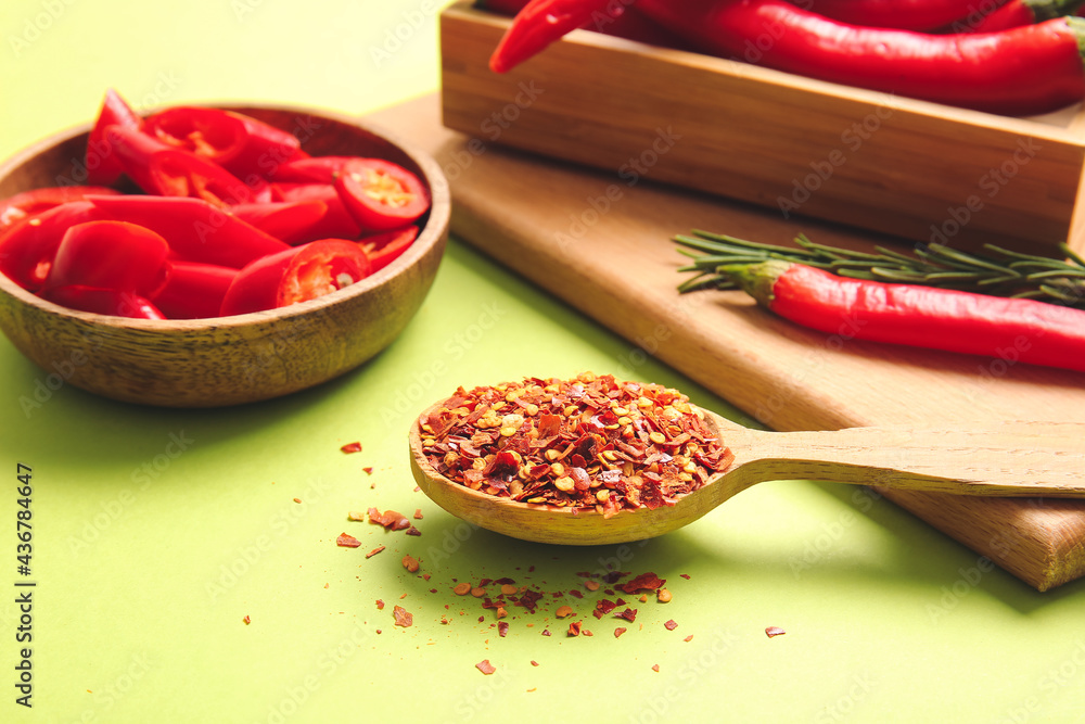 Spoon with ground hot chili pepper on color background