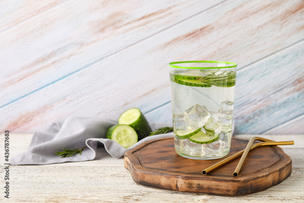 Glass with cucumber lemonade on light wooden background