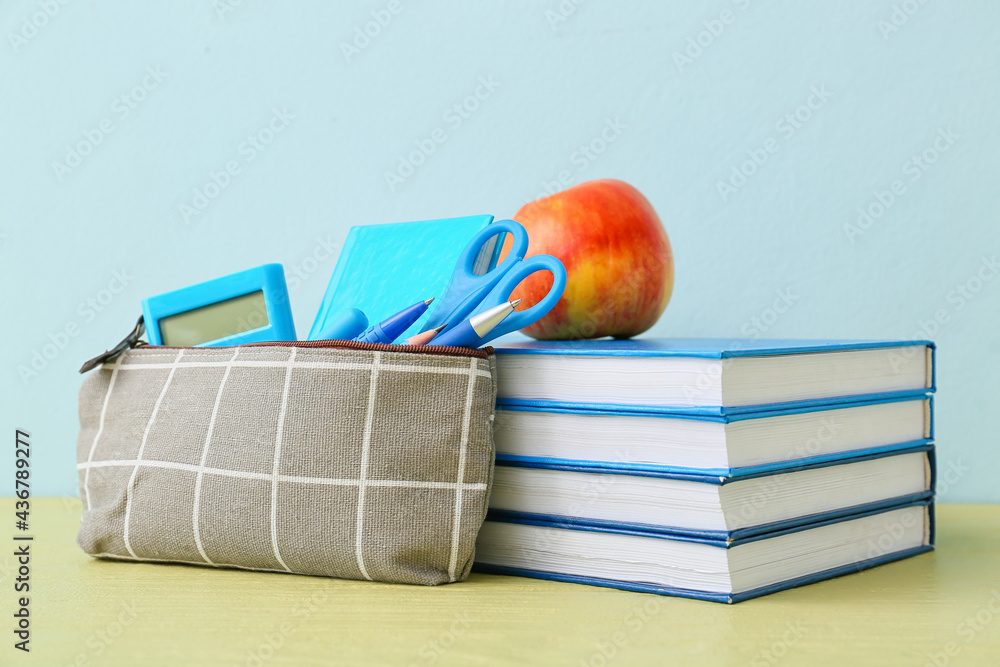 Pencil case and stationery on color background