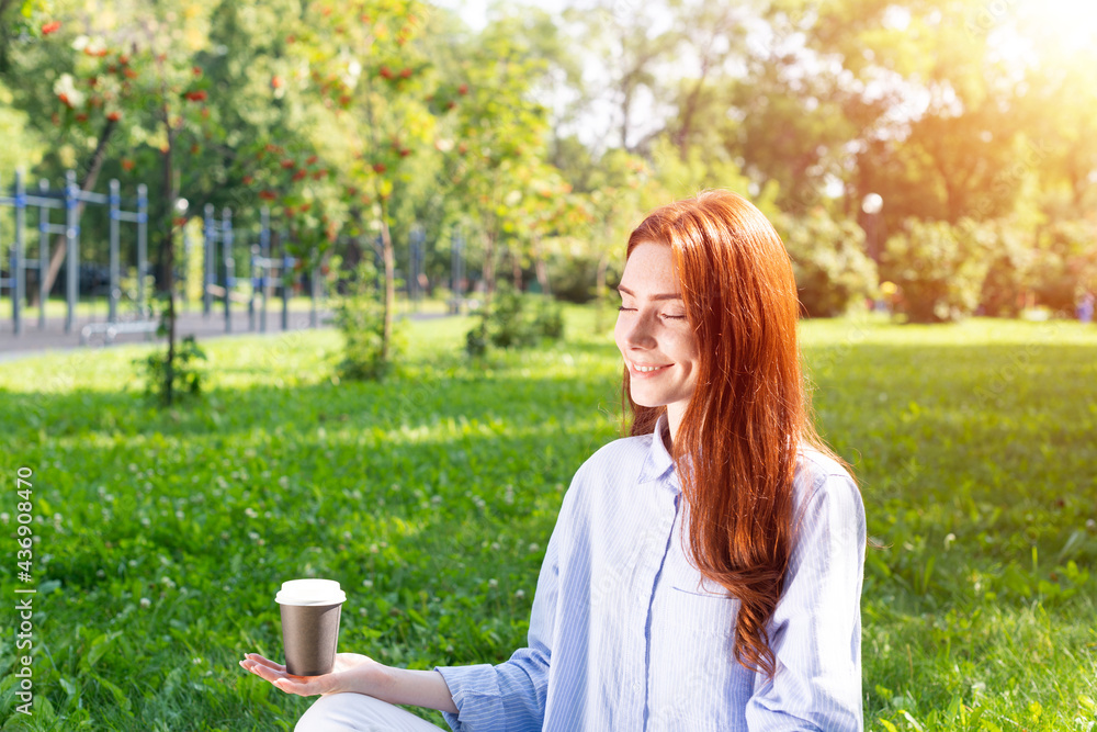 Young redhead woman meditates in lotus pose