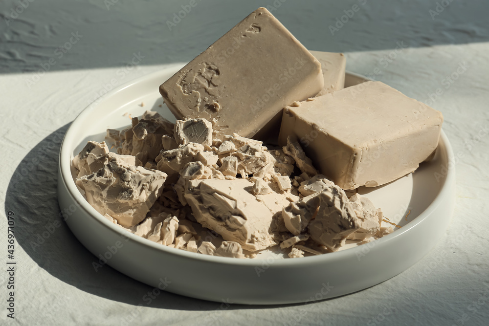 Plate with fresh yeast on light background