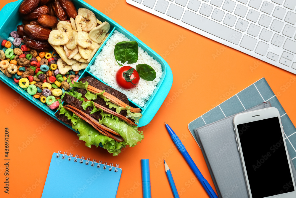 Lunchbox with tasty food, stationery and mobile phone on color background