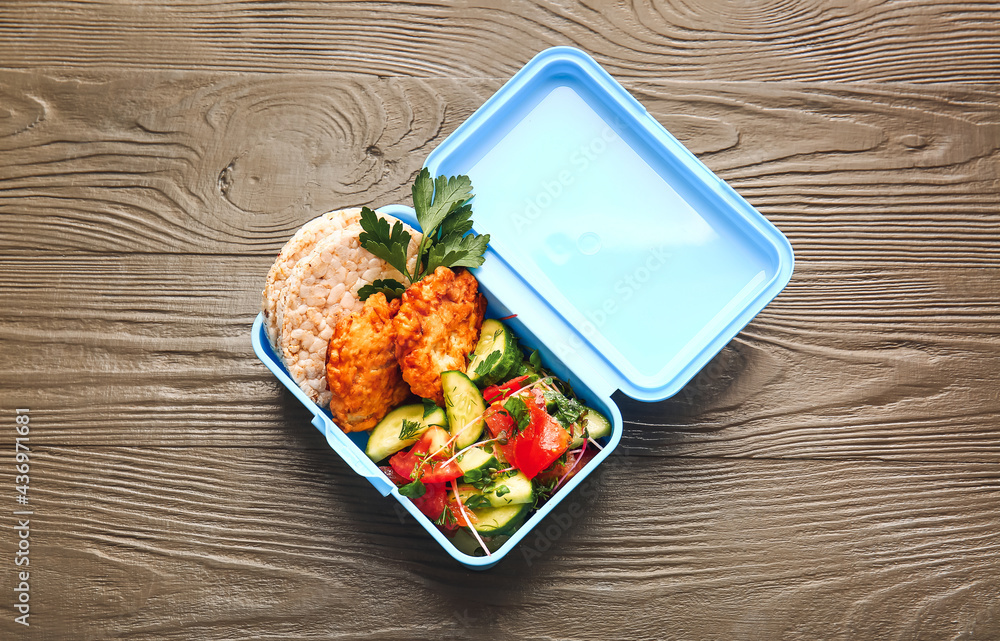 Lunch box with tasty food on wooden background