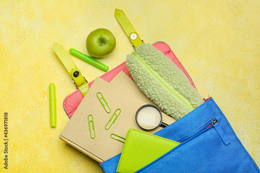 Backpack with pencil case and stationery on color background