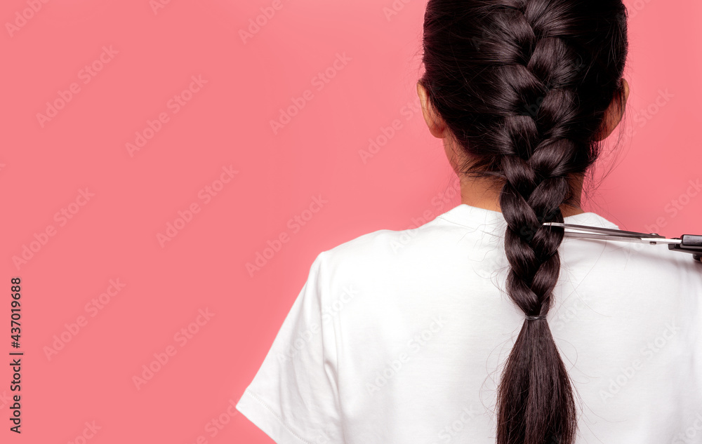 Back view of Asian woman with braided hairstyle is cutting with scissors for donate to cancer patien