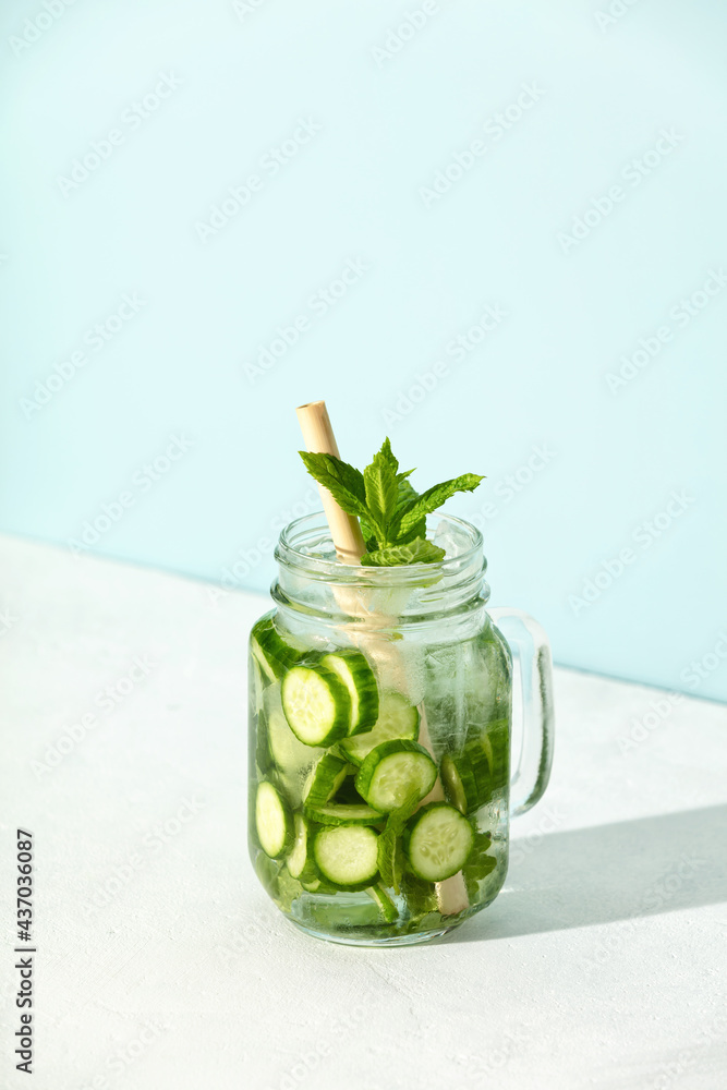 Homemade refreshing water with mint and cucumber in a mason jar with hard light and shadows