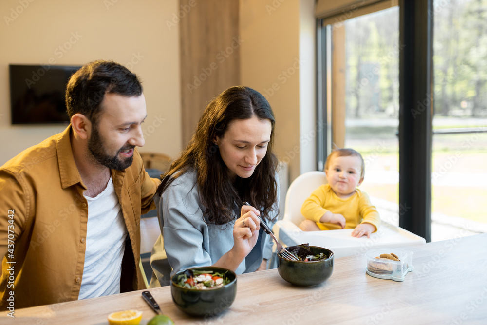 Young happy family with a one year baby boy during a lunch time at home. Concept of healthy vegan ea