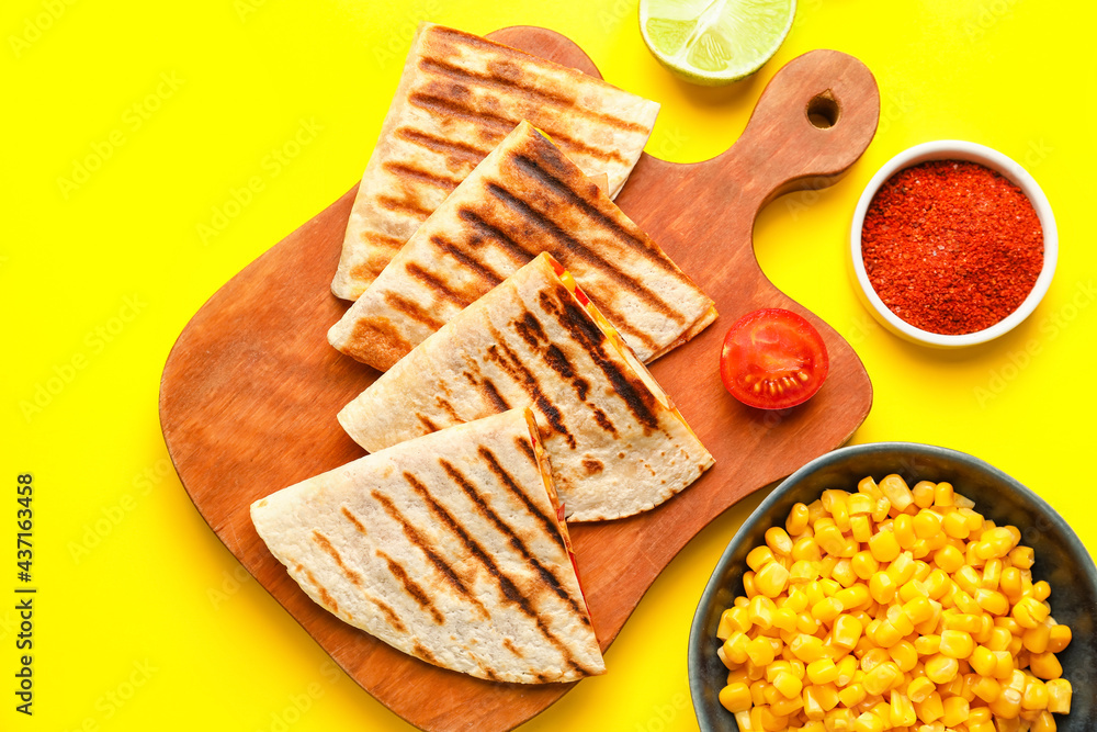 Board with tasty quesadillas, lime, corn and spices on color background