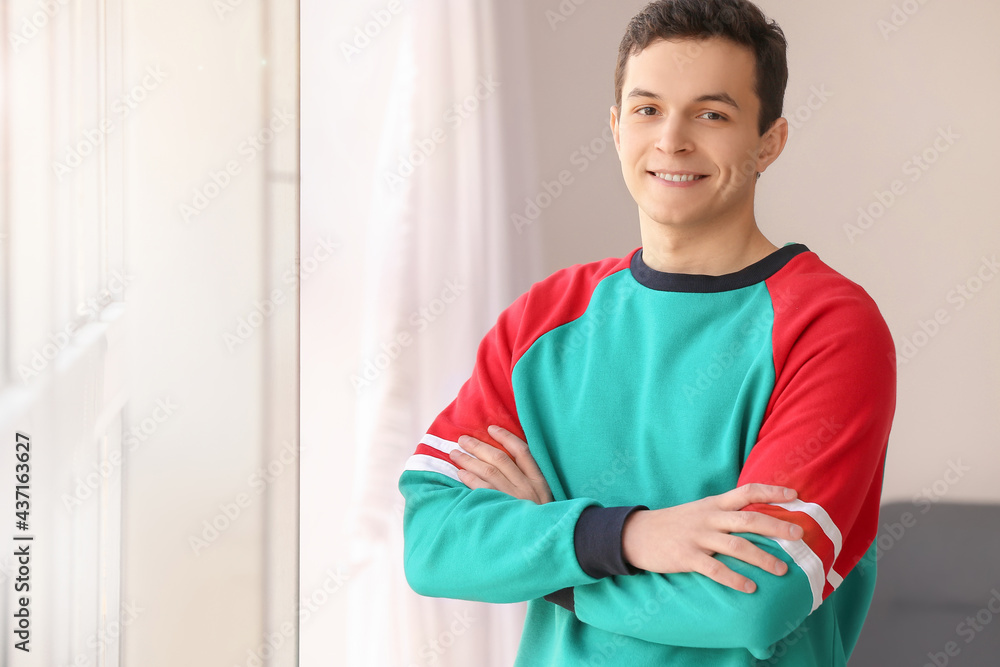 Handsome young man near window at home