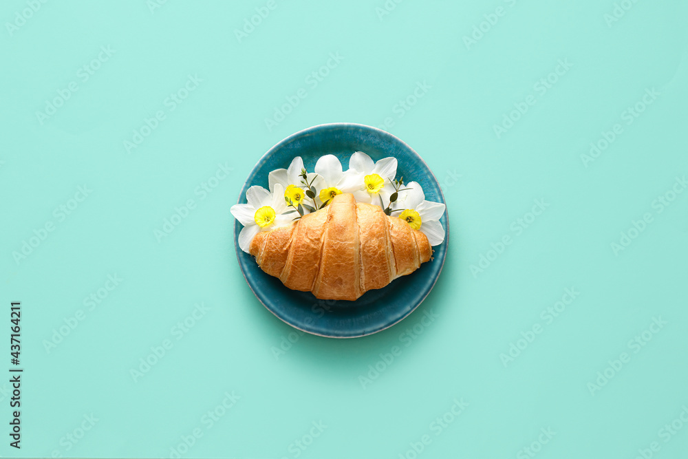 Tasty croissant with beautiful flowers on color background