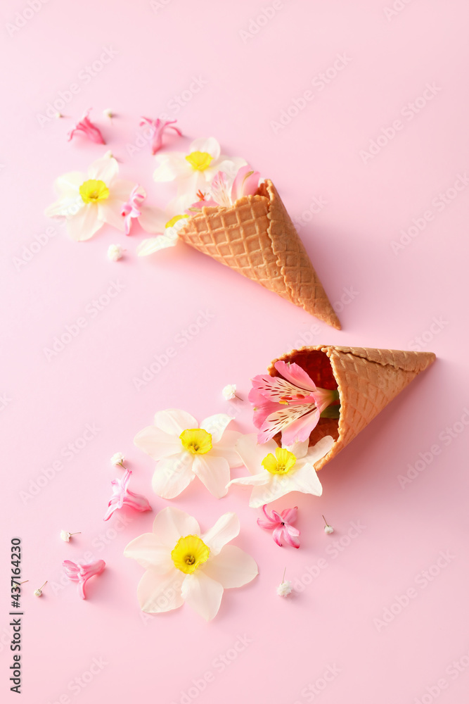 Waffle cones with beautiful flowers on color background