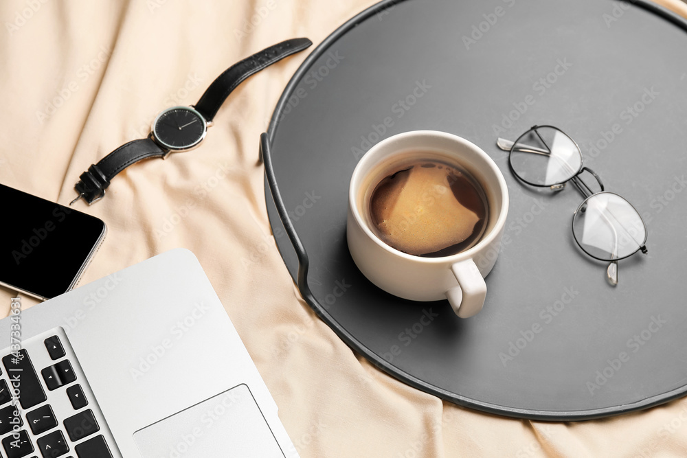 Composition with cup of coffee and glasses on bed