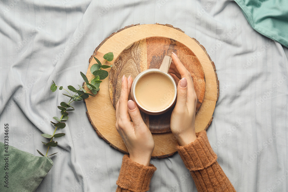 Woman with cup of coffee on bed