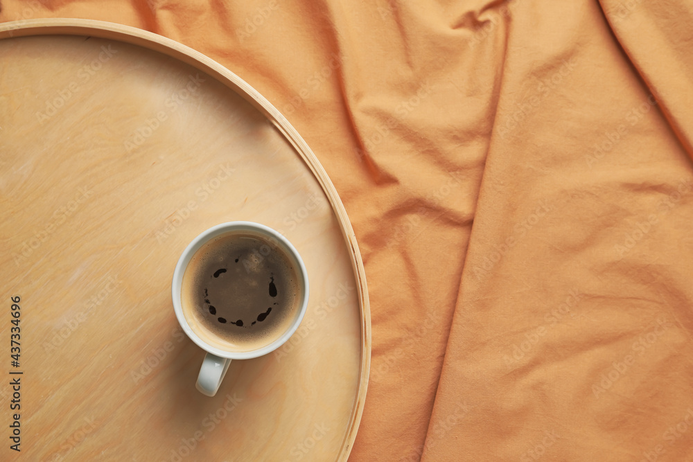 Tray with cup of coffee on bed