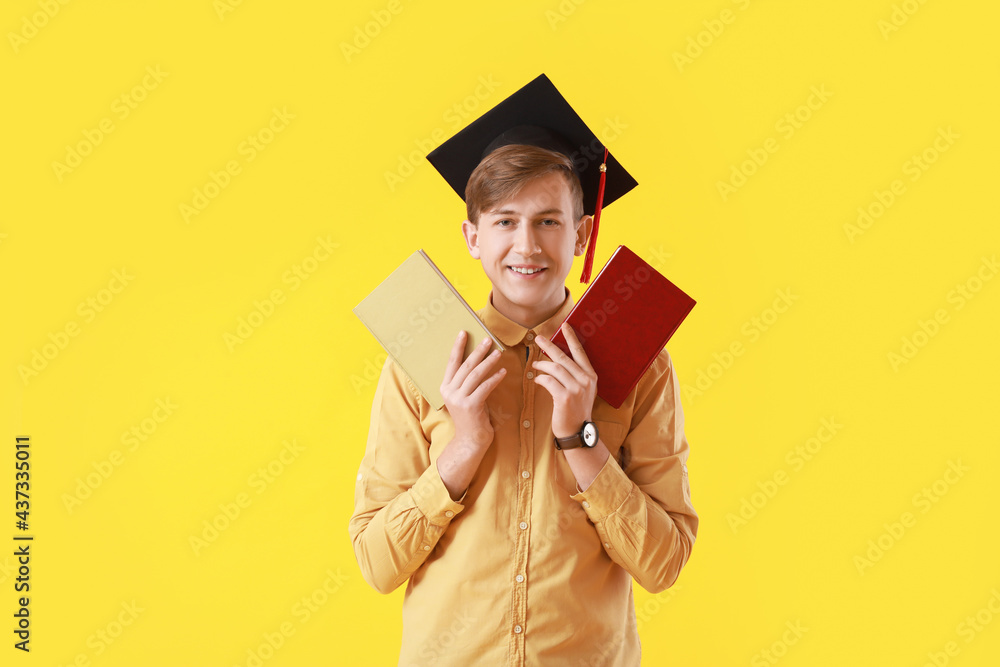 Male graduating student with books on color background