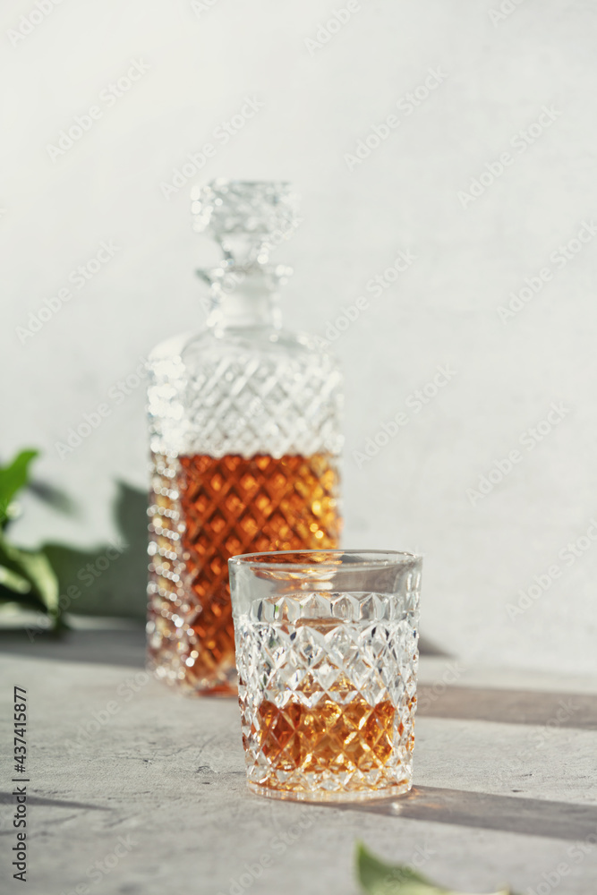 Glass of whiskey with ice cubes and carafe close up