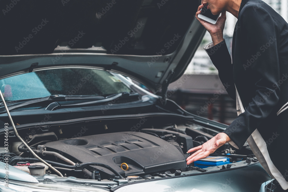 Young businesswoman whose car breakdown uses mobile phone to call for roadside assistance service. T