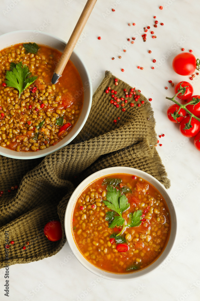 Bowls of tasty lentil soup on white background