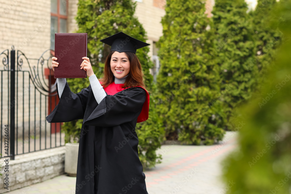 Female student in bachelor robe and with book on her graduation day