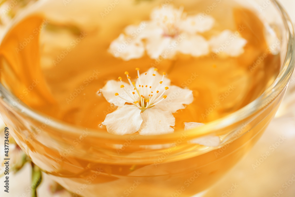 Cup with tasty tea and blooming fruit tree flowers, closeup