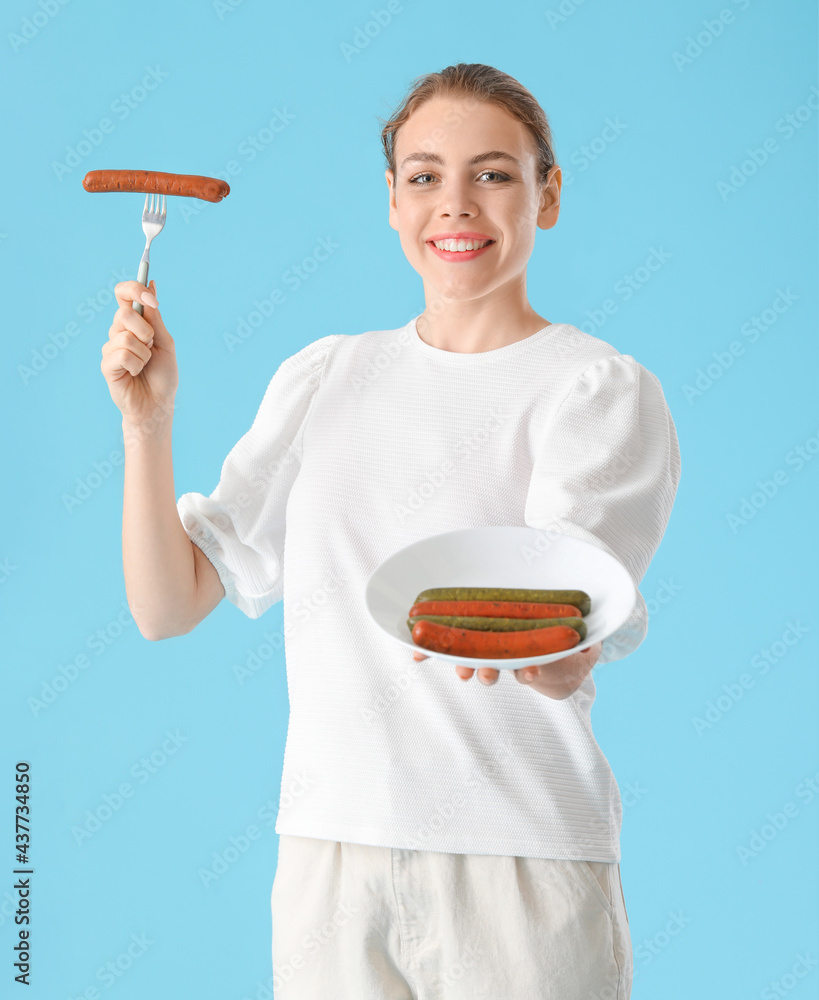 Young woman with tasty sausages on color background