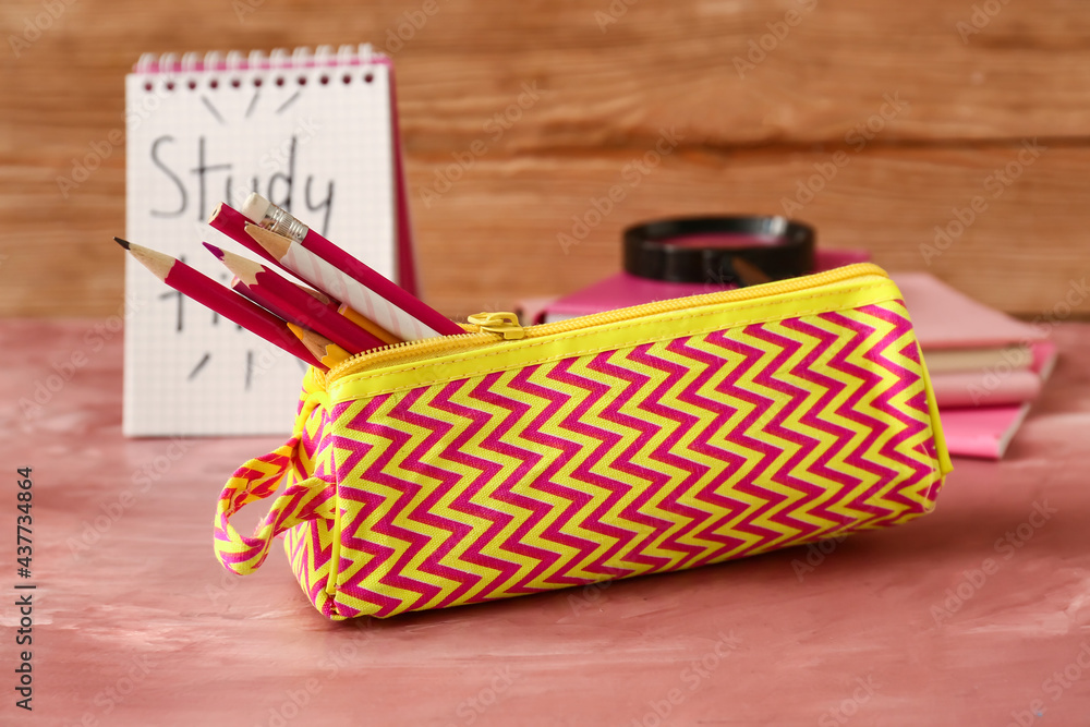 Pencil case with stationery on color background