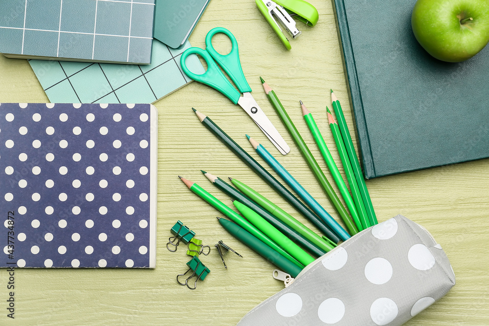 Pencil case and stationery on color wooden background