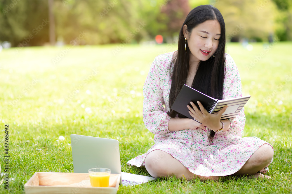 Working outside in summer or spring and WFH concept, Young beautiful Asian woman reading a book and 