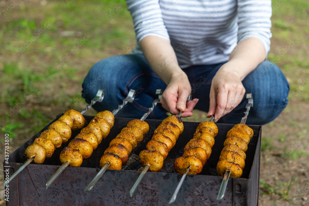 Mushrooms are roasted on fire on metal skewers over charcoal. Champignons grilled on brazier. Close-