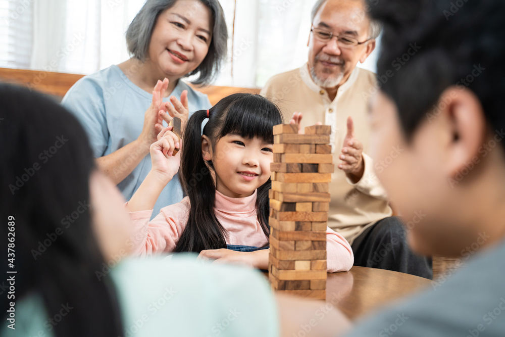 Asian big family cheering kid playing wooden block in the living room