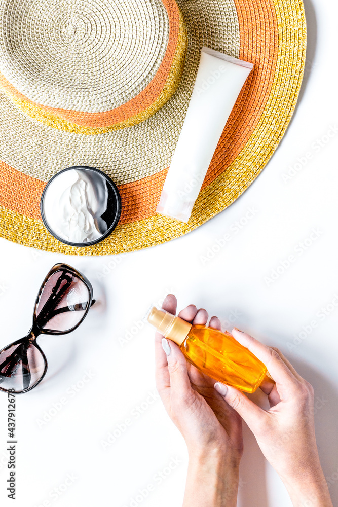 Summer rest with protiction cream, hat, hands white desk top view