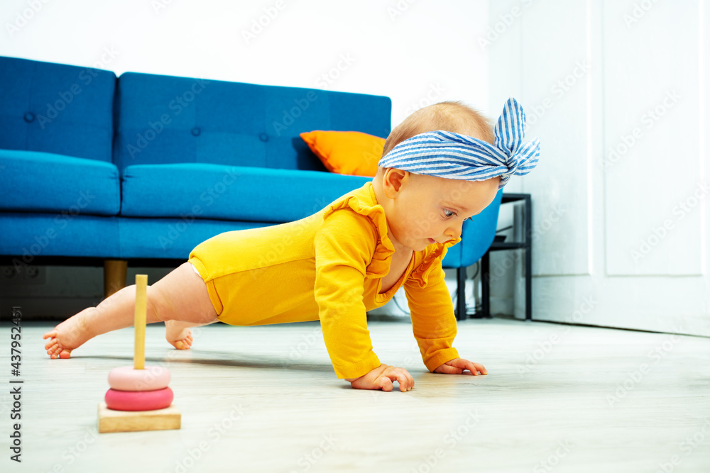 baby girl stand on legs and hands holding plank