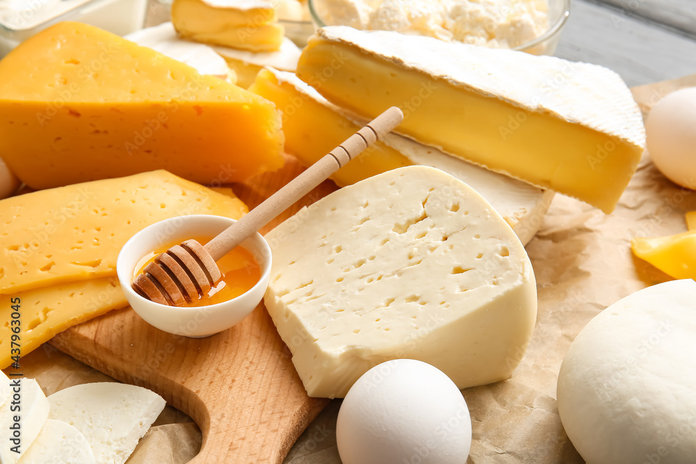 Tasty cheeses and honey on table, closeup