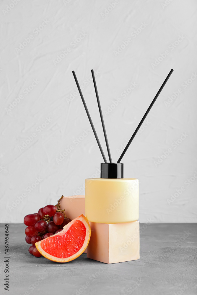 Reed diffuser with fruits on table against light background