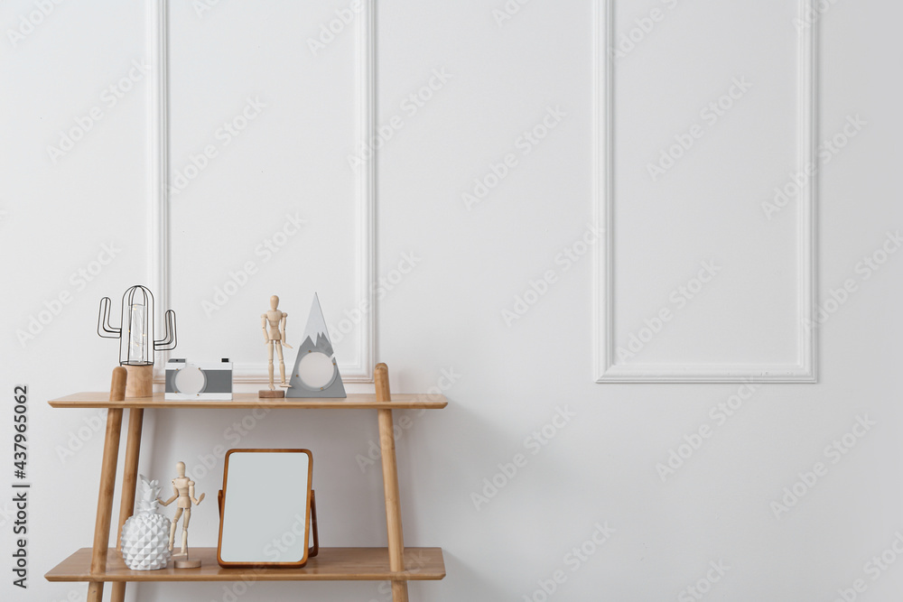 Modern shelf with mirror and decor near light wall