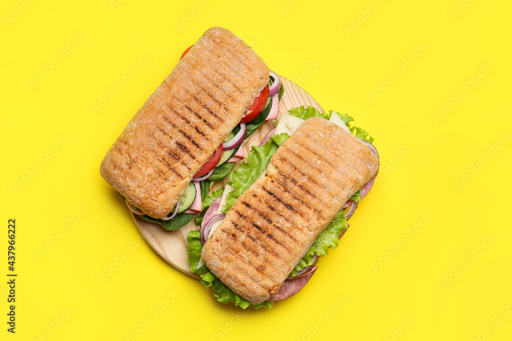 Board with tasty ciabatta sandwiches on color background