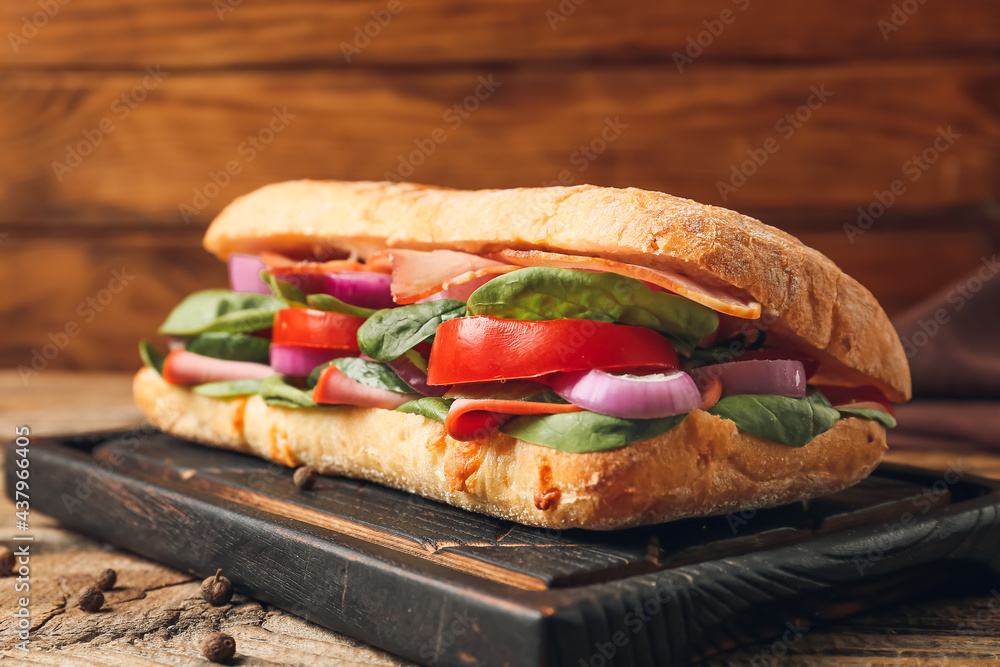 Board with tasty ciabatta sandwich on wooden background