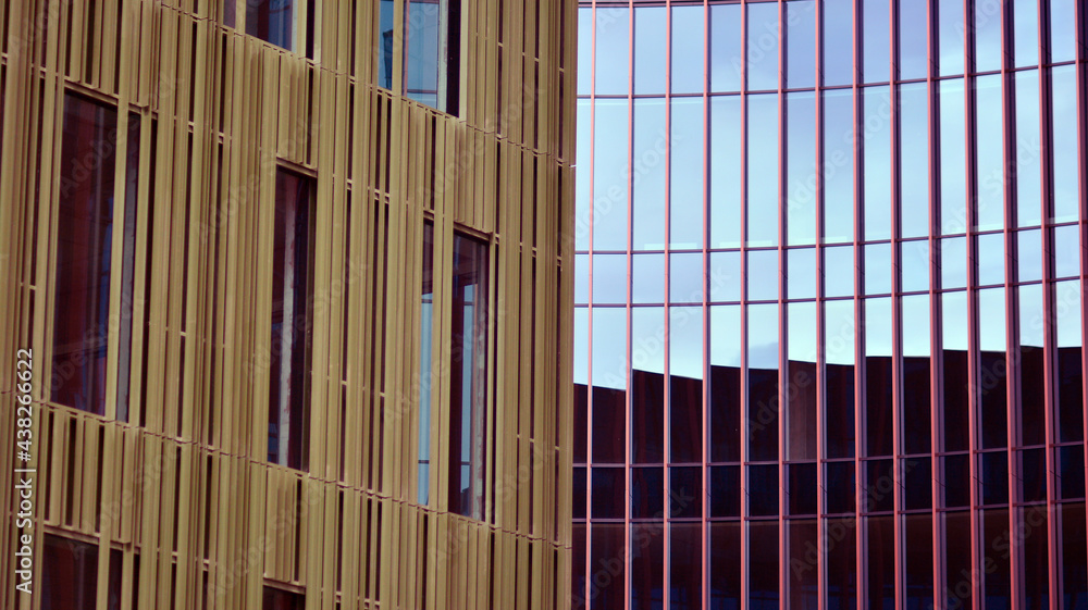 Abstract closeup of the glass-clad facade of a modern building covered in reflective plate glass. Ar