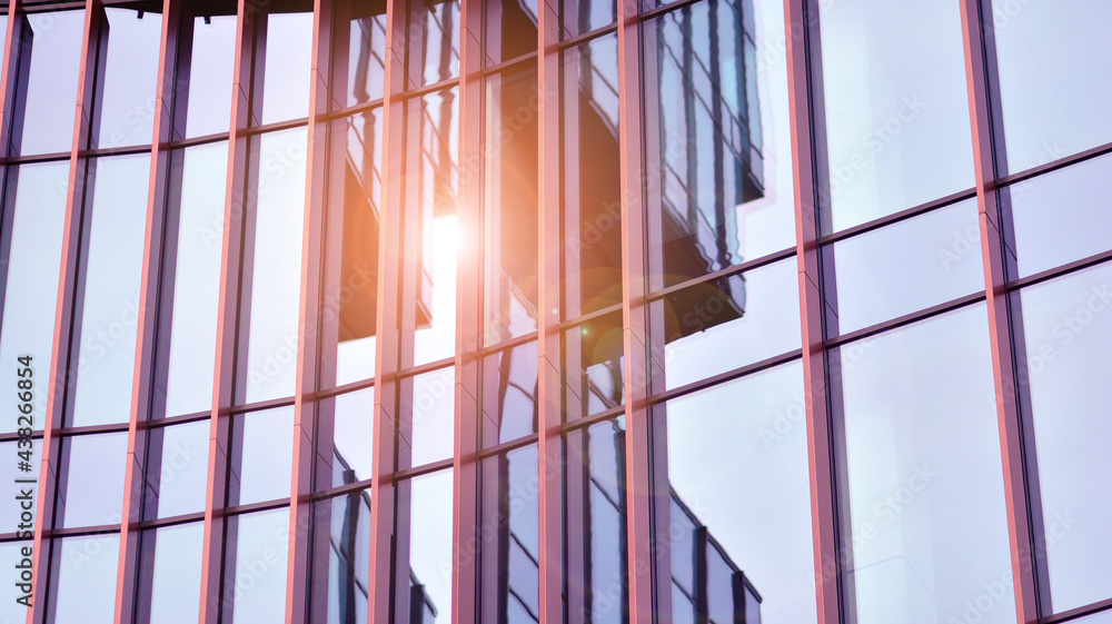 Abstract closeup of the glass-clad facade of a modern building covered in reflective plate glass. Ar