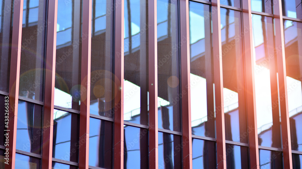 Abstract closeup of the glass-clad facade of a modern building covered in reflective plate glass. Ar