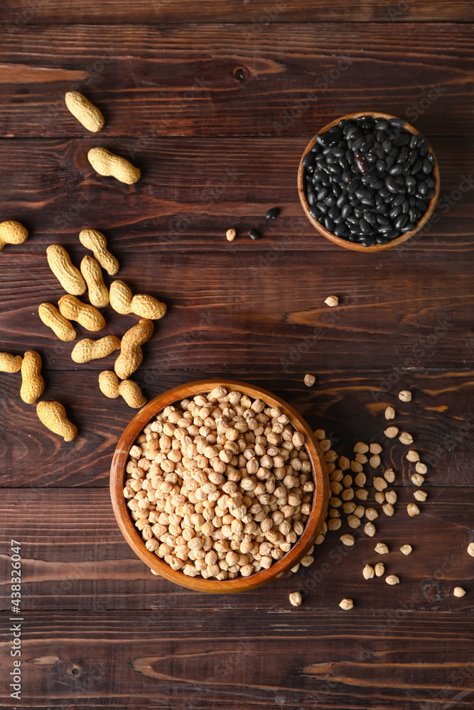 Bowls with different legumes on wooden background