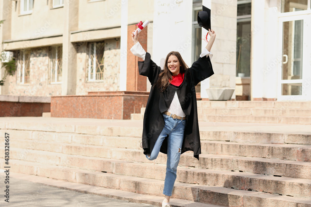 快乐的女学生，穿着学士长袍，毕业当天拿着文凭