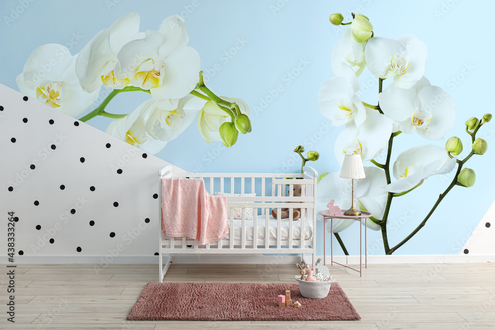 Stylish interior of childrens room with beautiful orchid flowers on wall