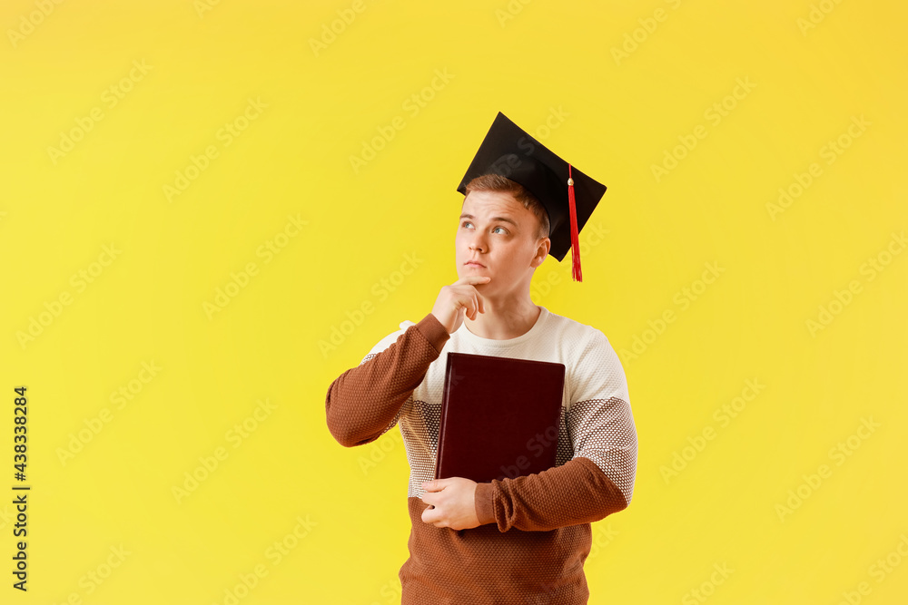 Thoughtful graduating student on color background