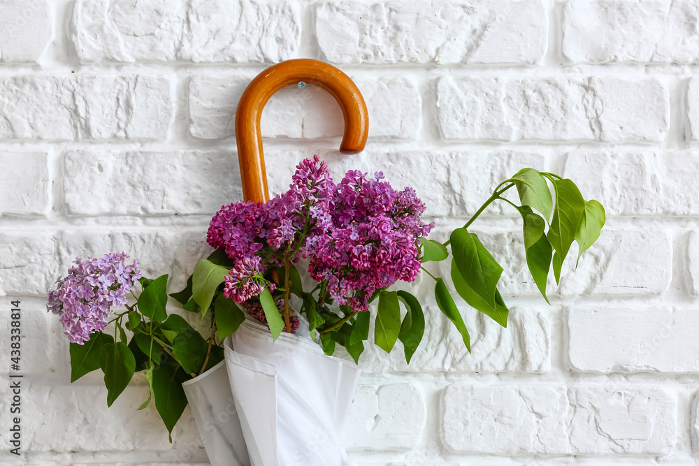 Umbrella with lilac flowers hanging on brick wall, closeup