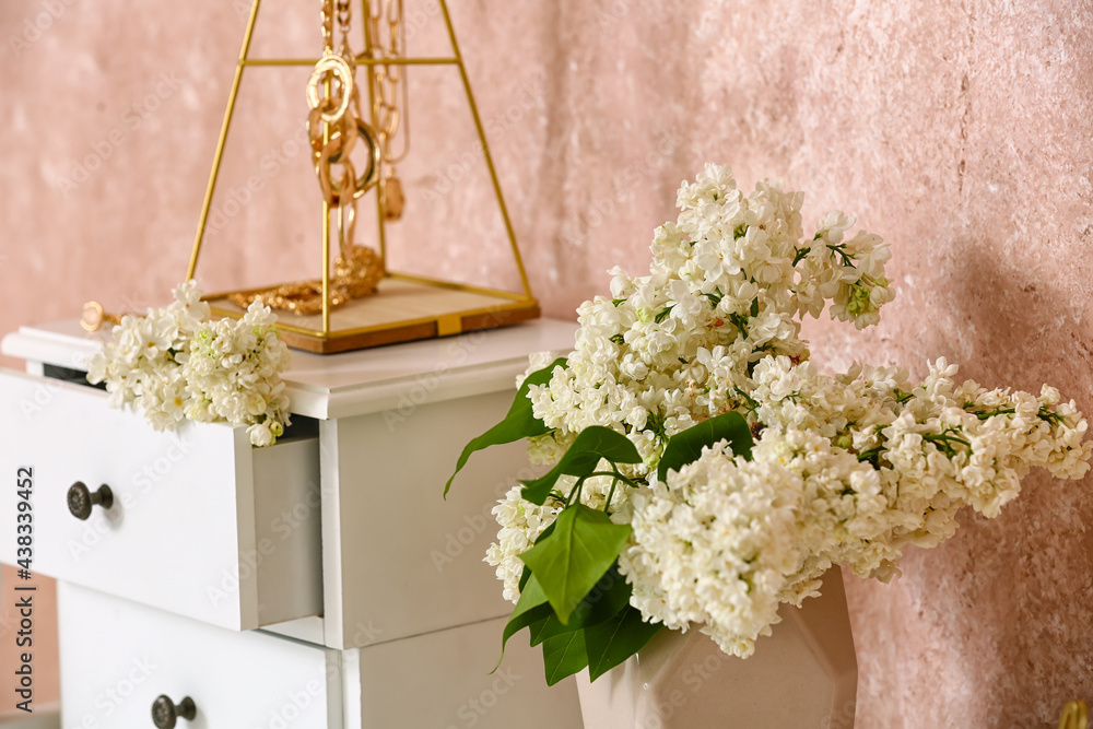 Vase with lilac flowers on table near color wall